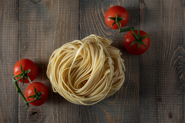 raw egg noodles with tomatoes on wood - Photo, Image