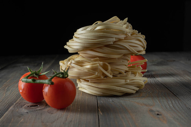 raw egg noodles with tomatoes stacked on wood - Photo, Image