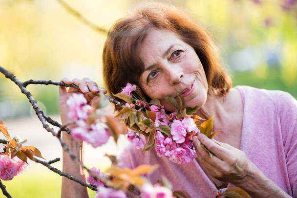Beautiful senior woman standing outside in spring nature. Copy space. - Fotografie, Obrázek
