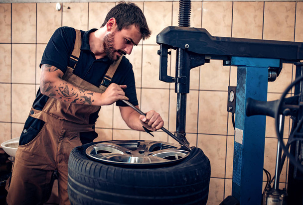 Handsome young man changing tires - 写真・画像