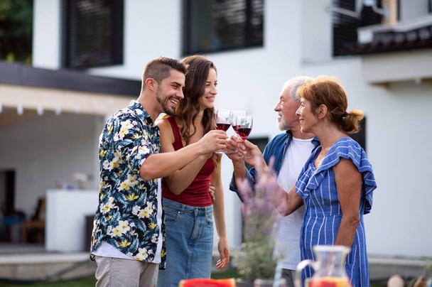 Portrait of people with wine outdoors on family garden barbecue. - Foto, afbeelding