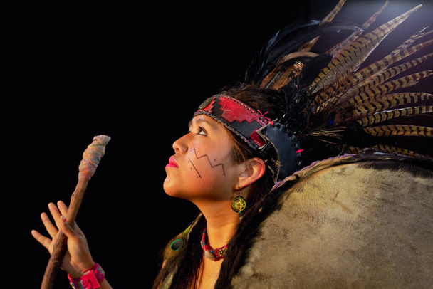 крупным планом молодой женщины Teotihuacana, Xicalanca - Toltec в черном фоне, с традиционным танцем платье с атрибутами с перьями и барабаном
 - Фото, изображение