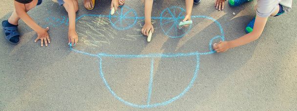 children draw a car with chalk on the pavement. selective focus. - Φωτογραφία, εικόνα