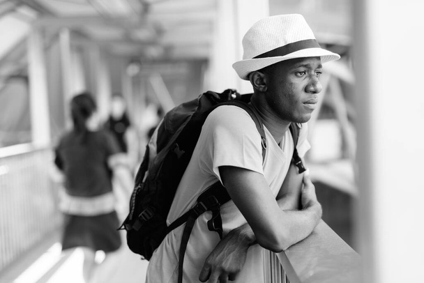 Jeune touriste africain réfléchissant en regardant loin la passerelle de la station de métro - Photo, image