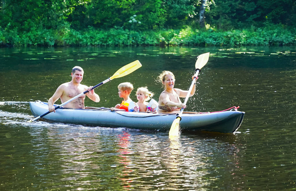 Молода сім'я з сином і дочкою катаються на байдарках на озері
 . - Фото, зображення