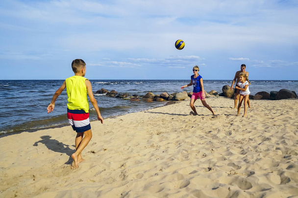 A family with a son and daughter playing with a ball on the beach. - 写真・画像