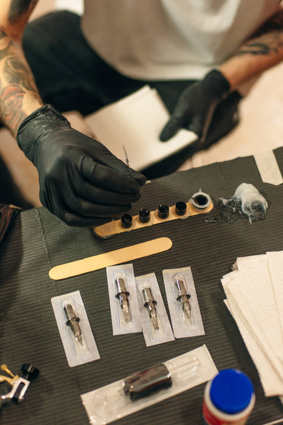 Tattoo artist workplace with machine and bottles with black tattoo ink - Foto, Imagen