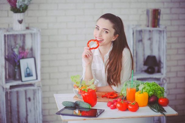 Pretty girl preparing fresh vegetable salad in her kitchen - Фото, зображення