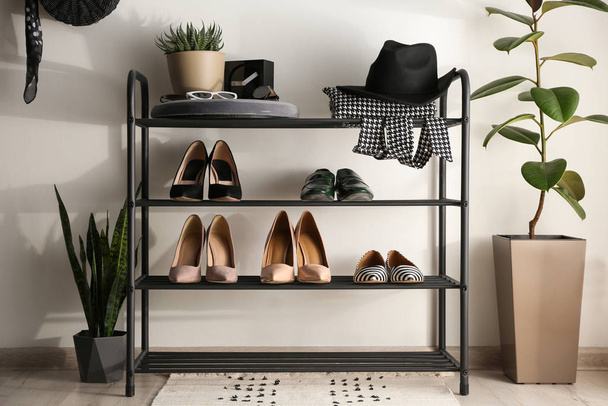 Black shelving unit with shoes and different accessories near wh - Фото, изображение