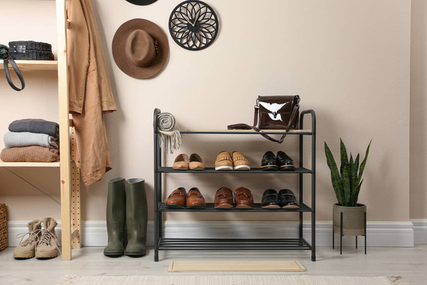 Rack with different shoes near beige wall in room - Foto, immagini