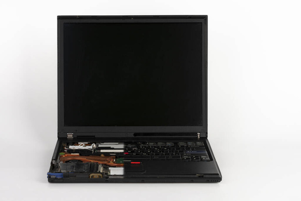 Старий ноутбук, видалена половина клавіатури на білому фоні, видимий помаранчевий куп вентилятор з тепловою раковиною
 . - Фото, зображення
