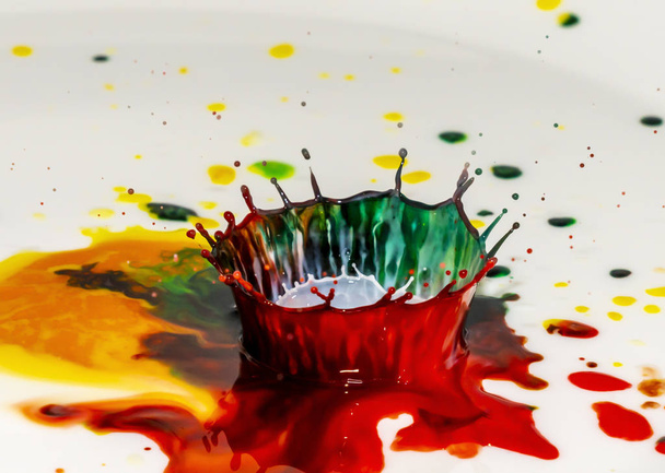 Εκρήξεις πολύχρωμων φωτεινών χρωμάτων βαφής με τη μορφή στεφάνων και πολύχρωμων πιτσιλιών - Φωτογραφία, εικόνα