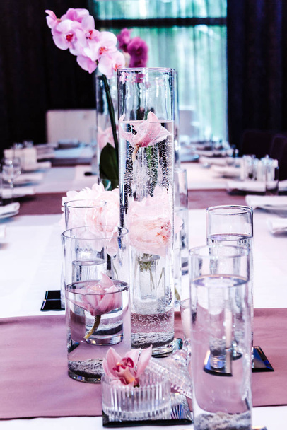 Sirviendo mesas en un restaurante con peonías y orquídeas
 - Foto, imagen