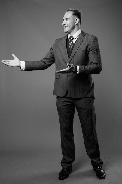Студийный снимок бизнесмена в иске на сером фоне в черно-белом - Фото, изображение