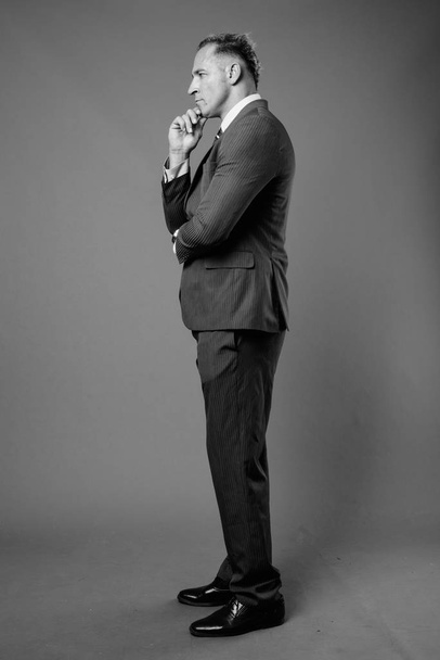 Студийный снимок бизнесмена в иске на сером фоне в черно-белом - Фото, изображение