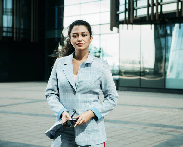 A young mulatto woman against the background of a business center is holding a mobile phone and talking. - Fotoğraf, Görsel