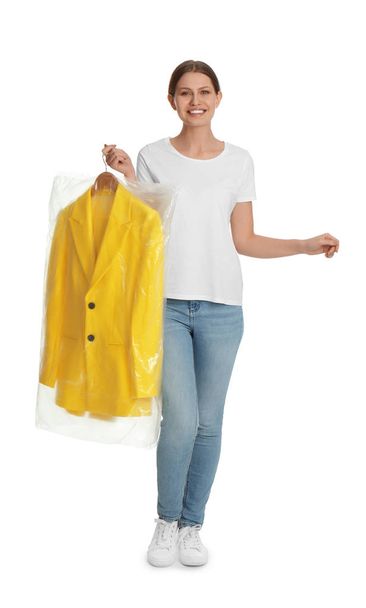 Young woman holding hanger with jacket in plastic bag on white background. Dry-cleaning service - Fotografie, Obrázek