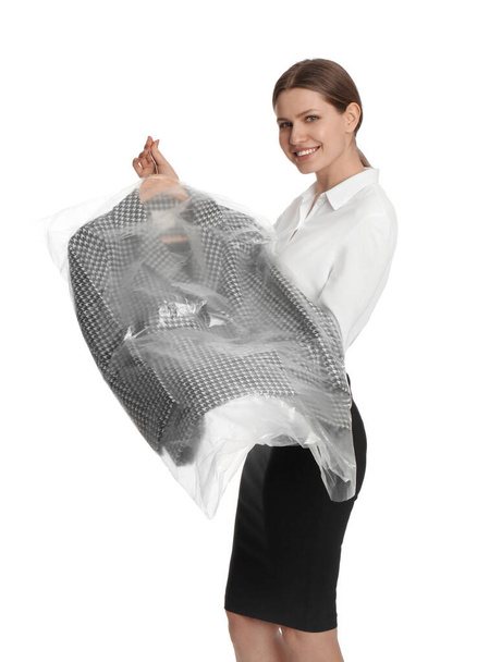 Young woman holding hanger with jacket in plastic bag on white background. Dry-cleaning service - Φωτογραφία, εικόνα