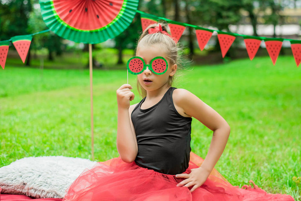 Wassermelonenparty, Picknick für Kinder im Park. Wassermelonen-Tag. Nettes kleines Mädchen mit Brille - Foto, Bild