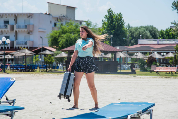 Mooi meisje met een tas in een strand. mooi tienermeisje rennen met koffer, wit zand, tropen bagage bestemming - Foto, afbeelding