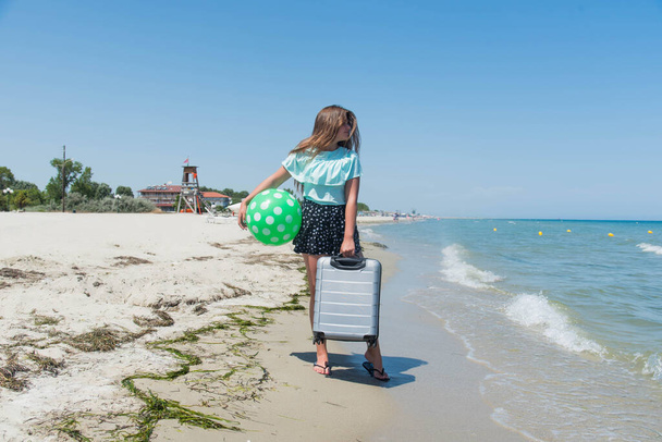 Krásná dívka s taškou na pláži. krásná dospívající dívka běží s kufrem, bílý písek, tropické zavazadla destinace - Fotografie, Obrázek