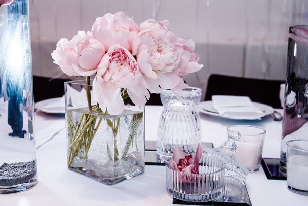 Şakayık ve orkidelerle dolu bir restoranda masa servisi. - Fotoğraf, Görsel