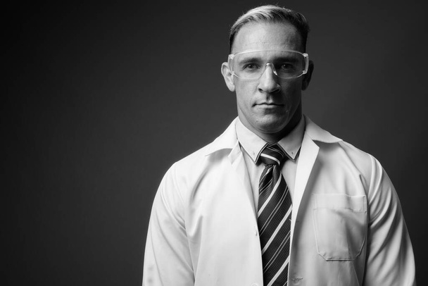 Stüdyo fotoğrafında doktor, siyah ve beyaz gri arka planda koruyucu gözlük takıyor. - Fotoğraf, Görsel