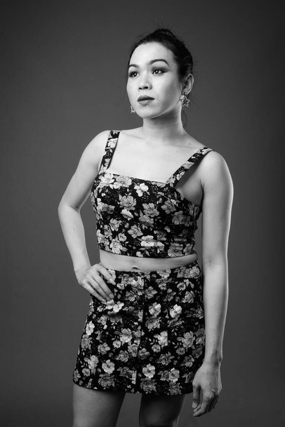 Studio πυροβόλησε νεαρή όμορφη Ασίας τρανσέξουαλ γυναίκα γκρι φόντο σε μαύρο και άσπρο - Φωτογραφία, εικόνα