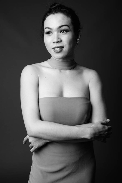 Студийный кадр молодой красивой азиатской трансгендерной женщины на сером фоне в черно-белом
 - Фото, изображение