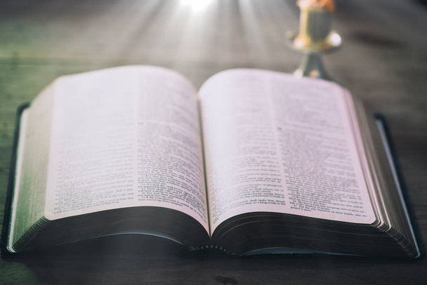 Открытая книга Священной Библии на деревянном столе у окна света
. - Фото, изображение