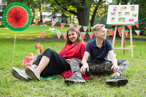 Aardig tienermeisje en jongen hebben plezier met watermeloen feest in het park. Uitstekend zonnig weer. Zomer concept. Watermeloen feestje, picknick, dag. - Foto, afbeelding