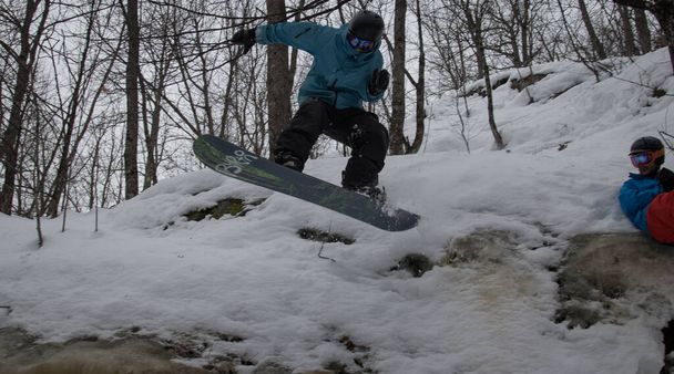 Snowboarder jumps off ice cliff in the woods - Photo, Image
