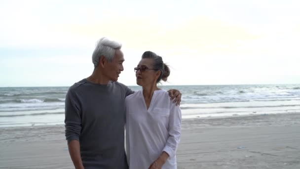 Aziatisch paar senior ouderling pensioen rusten ontspannen wandelen bij zonsondergang strand huwelijksreis familie samen geluk mensen levensstijl, slow motion beeldmateriaal - Video