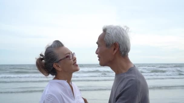 Ασιατικό ζευγάρι ηλικιωμένων συνταξιοδοτούνται χαλαρώστε φιλιά και αγκαλιάζει το ηλιοβασίλεμα παραλία μήνα του μέλιτος οικογένεια μαζί ευτυχία άνθρωποι τρόπο ζωής, Αργή κίνηση πλάνα - Πλάνα, βίντεο