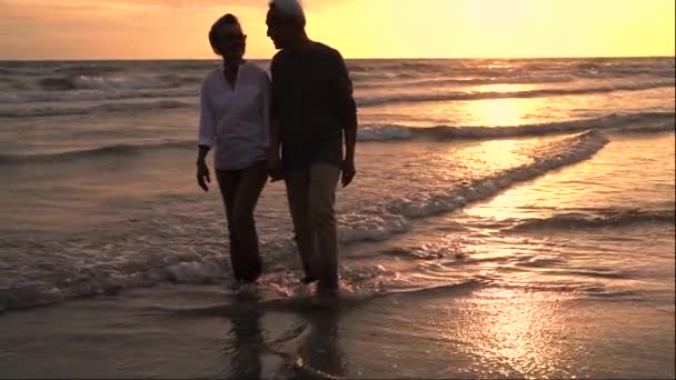 Aziatisch paar senior ouderling pensioen rusten ontspannen hand lopen bij zonsondergang strand huwelijksreis familie samen geluk mensen levensstijl, slow motion beeldmateriaal - Video