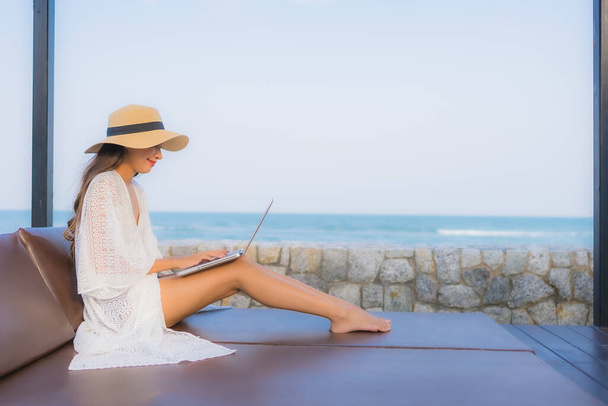 Портрет молодой азиатской женщины, использующей ноутбук вокруг пляжа
 - Фото, изображение