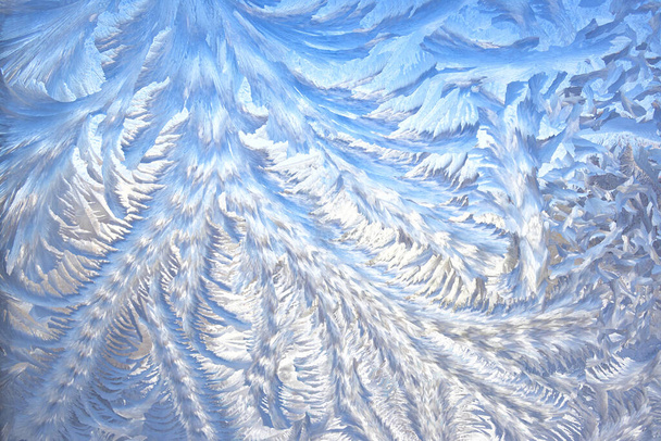 Foto van een bevroren raam. Prachtig natuurlijk vorstpatroon op winterraam. IJzige patronen op het glas. Winter fee achtergrond. - Foto, afbeelding