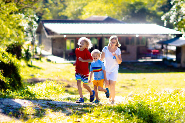 Mother and kids running outdoor at big house. - Fotografie, Obrázek