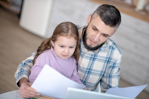 Serious dad with a daughter in her arms, with documents. - Foto, Imagen