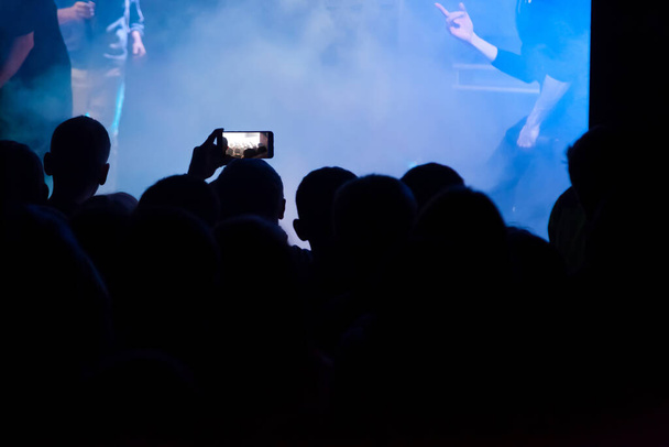 Рука со смартфоном записывает живой музыкальный фестиваль, делает фото
 - Фото, изображение