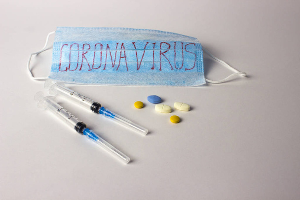 lékařská maska s nápisem coronavirus s injekčními stříkačkami a tabletami - Fotografie, Obrázek