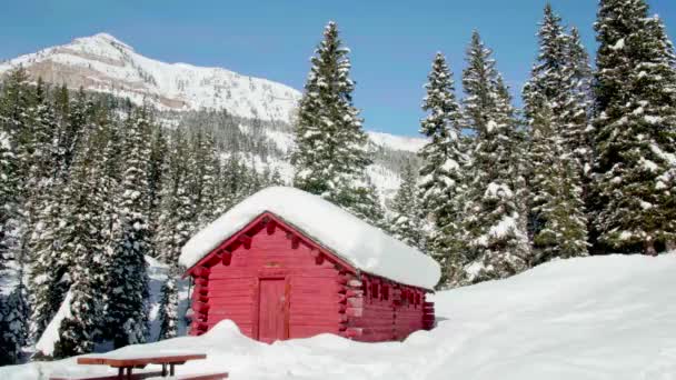 close up of log cabin in the winter with snow covered mountains in the background - Footage, Video