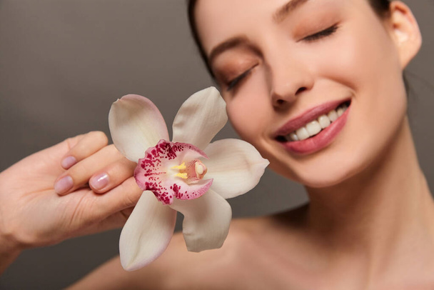 Uma jovem senhora branca sorridente com uma flor de orquídea
. - Foto, Imagem
