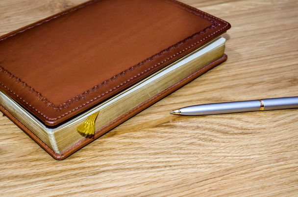 closed old brown leather notebook and fountain pen on wooden boards - Фото, изображение