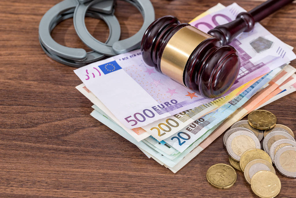 наручники з юридичним молотком і євро рахунки, монета на столі. бізнес-концепція
. - Фото, зображення
