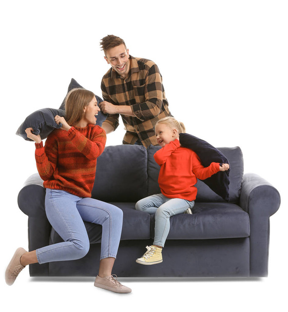 Szczęśliwa młoda rodzina walczy z poduszkami na kanapie na białym tle - Zdjęcie, obraz