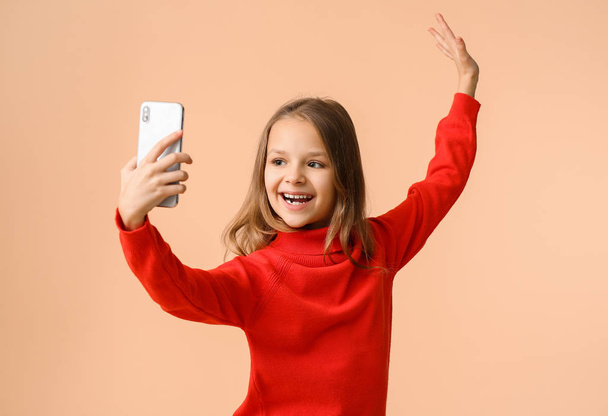 schattig klein meisje het nemen van selfie op kleur achtergrond - Foto, afbeelding