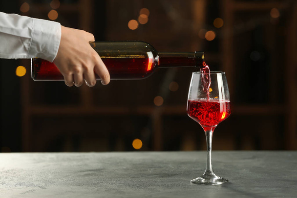 Pincér finom bort tölt palackból üvegbe az asztalon a bárban - Fotó, kép
