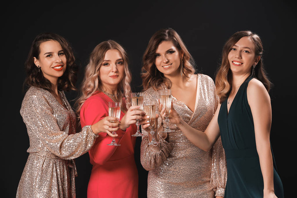 Beautiful young women with champagne on dark background - Foto, Imagen