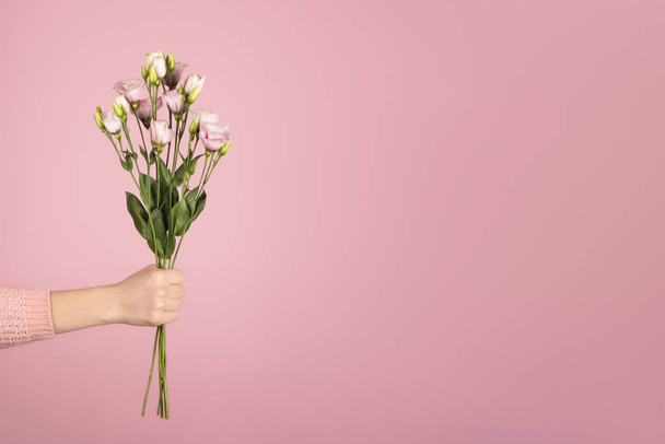 Beautiful bouquet of pink Eustoma in a female hand on pink background. Copy space - Foto, immagini